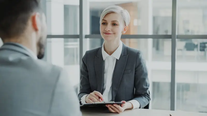An interviewer taking notes during an interview in a bright office.
